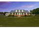 Charming brick home with a well-manicured lawn, dormer windows, and mature trees under a colorful sunset at 201 Wendy Pl, Benson, NC 27504