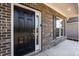 Home exterior featuring a black front door, brick facade, and a window with shutters at 2221 Holtwood Way, Apex, NC 27523