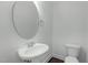 Well-lit powder room featuring a pedestal sink, round mirror, and a modern toilet at 2227 Rocky Bay Ct, Cary, NC 27519