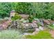 Beautiful stone entrance sign for WoodCreek community with lush landscaping and a water feature at 225 Mayfield Dr, Apex, NC 27539