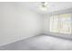 Bright bedroom featuring a ceiling fan, neutral carpet, and a large window with vertical blinds at 2421 Kudrow Ln, Morrisville, NC 27560