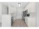 Contemporary kitchen featuring white cabinetry, modern stainless steel appliances, and sleek laminate flooring at 2421 Kudrow Ln, Morrisville, NC 27560