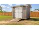 A gray and white shed with a wooden ramp provides extra storage in the backyard at 25 Cornfield Ln, Benson, NC 27504