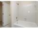 Bathroom featuring a standard bathtub with white tiled walls and a showerhead, adjacent to a white paneled door at 2901 Hunters Bluff Dr, Raleigh, NC 27606