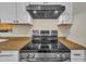 Close-up of modern stainless steel stove with black cooktop and range hood above at 3116 Henslowe Dr, Raleigh, NC 27603