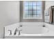 Clean white bathtub with chrome fixtures and a frosted window at 312 Loon Ct, Graham, NC 27253
