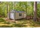 Well-maintained storage shed with a garage door, side entry, and surrounded by lush greenery at 3312 Shannon Cir, Apex, NC 27539