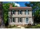 Charming two-story home featuring a blue front door, neutral siding, and black shutters, set amidst mature trees and green lawn at 3317 E Jameson Rd, Raleigh, NC 27604