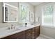 Modern bathroom with double vanity, white countertops, dark wood cabinets and bright, reflective lighting at 337 Merrywood Dr, Raleigh, NC 27610