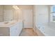 Bright bathroom featuring a double sink vanity with white cabinets and a separate soaking tub at 367 Fenella Dr, Four Oaks, NC 27524