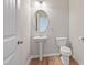 Bathroom features a pedestal sink, oval mirror, wood flooring, and toilet at 367 Fenella Dr, Four Oaks, NC 27524