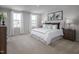 Sunlit bedroom with two windows features a plush bed with decorative pillows and neutral decor for a calming retreat at 368 N Coral Bells Way, Four Oaks, NC 27524