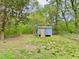 View of a blue storage shed in a green backyard with mature trees and a fence at 409 Neathery St, Henderson, NC 27536