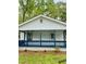 Front view of home featuring a cozy front porch with blue accents and well-kept landscaping at 409 Neathery St, Henderson, NC 27536