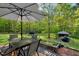 Inviting backyard featuring a dining area, grill, garden bed, and a canopy in a wooded setting at 452 Dogwood Trl, Henderson, NC 27537
