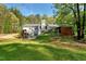 Expansive backyard featuring a large lawn, mature trees, the rear of the home, and an outside canopy at 452 Dogwood Trl, Henderson, NC 27537