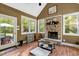 Cozy sunroom features a stone fireplace, wood floors, and lots of natural light at 452 Dogwood Trl, Henderson, NC 27537