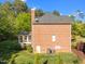 Brick house featuring a sunroom, chimney, and backyard with lush greenery at 5016 Dillswood Ln, Raleigh, NC 27606
