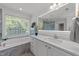 Bathroom featuring a white vanity, soaker tub, a large window, and a separate walk-in shower at 5016 Dillswood Ln, Raleigh, NC 27606