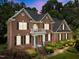 Charming brick home features a balcony, black shutters, lush landscaping, and an inviting entrance at 5016 Dillswood Ln, Raleigh, NC 27606