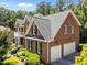 Brick home with manicured landscaping, white trim, dormer windows, and a three car garage at 5016 Dillswood Ln, Raleigh, NC 27606