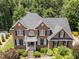 Beautiful two-story brick home featuring a charming balcony, black shutters, and lush landscaping at 5016 Dillswood Ln, Raleigh, NC 27606