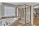 Bathroom featuring a shower with glass enclosure, soaking tub and window with decorative glass at 5109 Dove Forest Ln, Apex, NC 27539