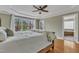 A spacious bedroom with hardwood floors, ceiling fan, large bed and access to the ensuite bath at 5109 Dove Forest Ln, Apex, NC 27539