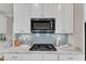 Close up of kitchen features stainless microwave, cooktop, and subway tile backsplash at 5109 Dove Forest Ln, Apex, NC 27539
