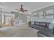 Relaxing living room featuring a leather sofa, ceiling fan, and stairs at 5109 Dove Forest Ln, Apex, NC 27539