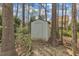 A small storage shed in the backyard with mature trees surrounding it at 5109 Dove Forest Ln, Apex, NC 27539