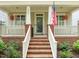 Inviting brick front porch with white railings, hanging floral baskets, and an American flag on display at 607 Millbrook Dr, Pittsboro, NC 27312
