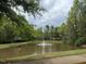 Picturesque pond with a fountain surrounded by lush greenery and mature trees at 607 Millbrook Dr, Pittsboro, NC 27312