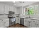 Bright kitchen featuring white cabinets, stainless steel appliances, and a large window at 626 Bailey Rd, Coats, NC 27521