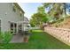 Backyard featuring a patio with dining set, lush landscaping, and a retaining wall at 712 Wellspring Dr, Holly Springs, NC 27540