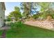 Landscaped backyard featuring a retaining wall with vibrant flower bushes and a patio with an umbrella-covered table set at 712 Wellspring Dr, Holly Springs, NC 27540