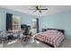 Well-lit bedroom featuring light blue walls, carpet, ceiling fan, and a work area at 712 Wellspring Dr, Holly Springs, NC 27540