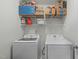 Functional laundry room with front-loading washer and dryer, plus overhead shelving at 712 Wellspring Dr, Holly Springs, NC 27540