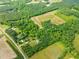 A sprawling acreage is shown from above, featuring a pond and plentiful trees at 7129 Dexter Rd, Oxford, NC 27565