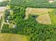Aerial view showcasing land with a pond and various structures in a mixed terrain setting at 7129 Dexter Rd, Oxford, NC 27565