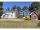 A full view of a white multi-story house and a separate red building with a metal roof at 7129 Dexter Rd, Oxford, NC 27565