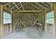 Unfinished interior of an outbuilding featuring exposed wood framing and natural light from two windows at 7129 Dexter Rd, Oxford, NC 27565
