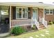 Charming brick home featuring a cozy covered porch with decorative plants and seating at 7698 Nc Highway 222, Kenly, NC 27542
