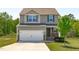 Two-story home features a two-car garage, neutral siding, and a well-maintained front yard with new tree at 80 Doonbeg Dr, Fuquay Varina, NC 27526