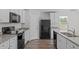 Modern kitchen featuring white cabinets, black appliances, and beautiful wood-look flooring at 80 Doonbeg Dr, Fuquay Varina, NC 27526