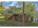 Back exterior featuring a deck with stairs to the backyard, a brick foundation, and mature trees at 8012 Glenbrittle Way, Raleigh, NC 27615
