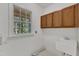 Functional laundry room with sink, storage cabinets, and a window with a nature view at 8012 Glenbrittle Way, Raleigh, NC 27615