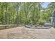 Spacious brick backyard patio area with a gravel fire pit area and lush trees surrounding the backyard at 8407 Millers Bnd, Bahama, NC 27503
