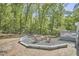 Outdoor brick patio area with a gravel fire pit and seating perfect for entertaining amongst lush trees at 8407 Millers Bnd, Bahama, NC 27503