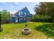 Spacious backyard features a fire pit, green grass, and a blue house with white trim at 909 Starkland Way, Holly Springs, NC 27540